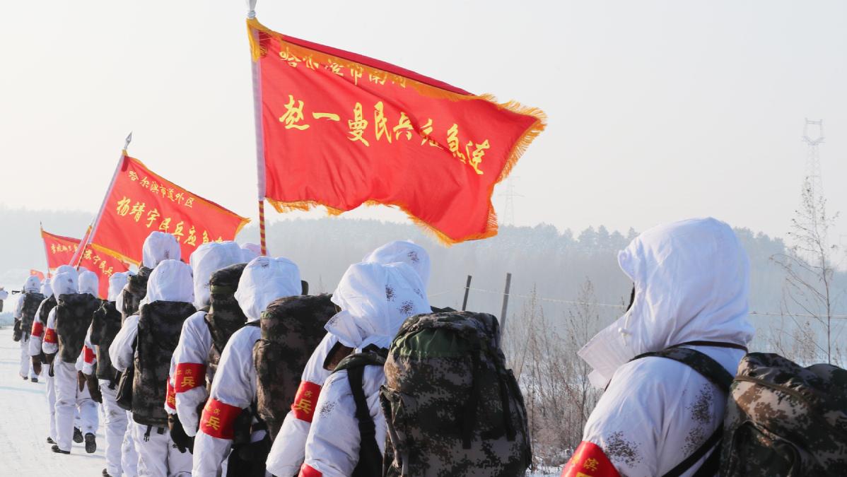 (图为哈尔滨市民兵高举"英雄旗"行进在冬训的林海雪原.孙健摄)