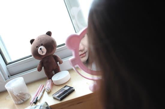 化妆中的大拿，镜子旁边放着她喜欢的布朗熊