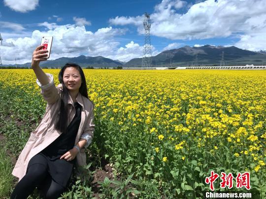 图为美女游客在油菜花海边自拍. 孙睿 摄