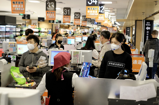 某超市内,消费者戴着口罩在收银台结算