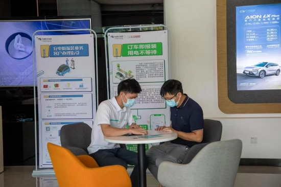 新能源汽车销售人员在为客户介绍“订车即报装,用电不等待”业务流程,新模式比以往报装节省40%等待时间。(黎颖仪 摄)