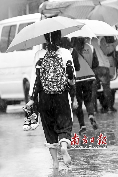 21日,深圳一位中学生在雨中赤脚行走. 南方日报记者 朱洪波摄
