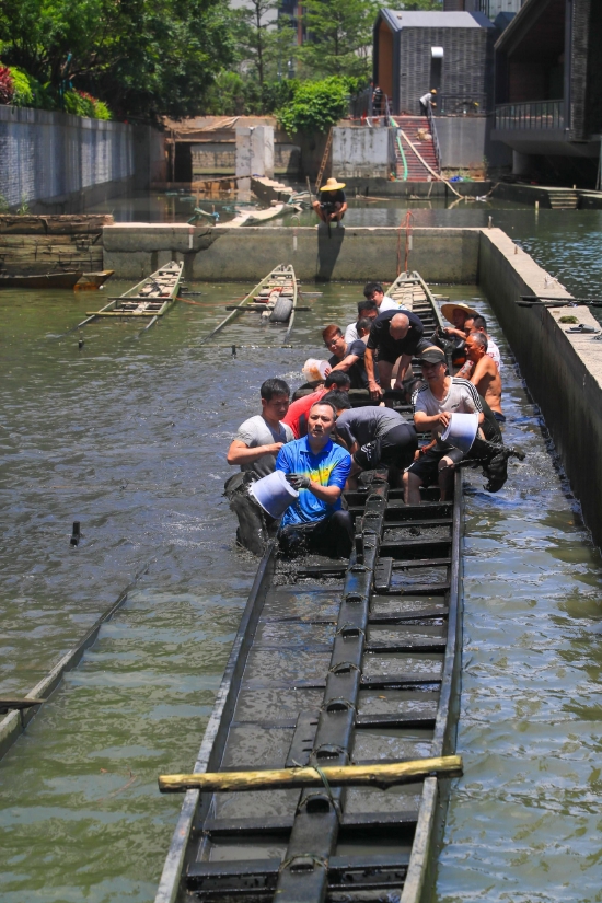广州市黄埔区文冲村举行“起龙”仪式。图为村民们将船身中的泥水舀出。李剑锋 摄