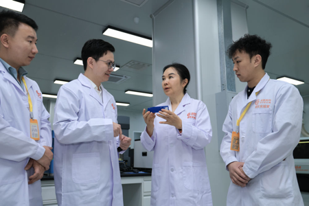 在广东鼎泰高科技术股份有限公司总部实验室，王馨（右二）与研发人员交流。新华社记者 毛思倩 摄