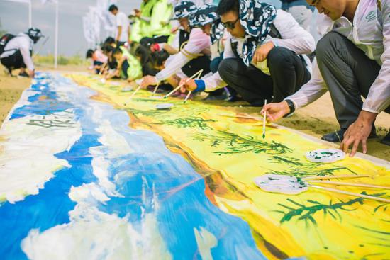 志愿者与当地小朋友共绘“绿动沙漠心愿成林”画卷