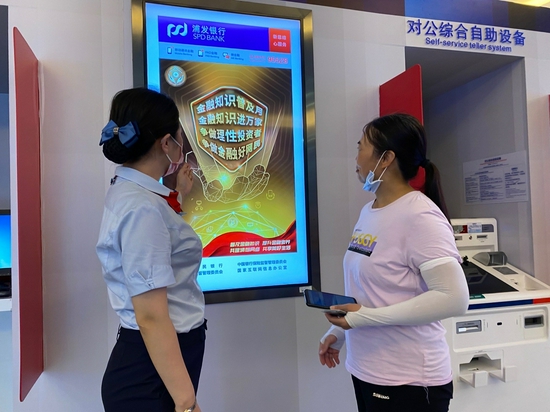 (浦发银行大堂经理在营业厅堂向消费者介绍活动内容)