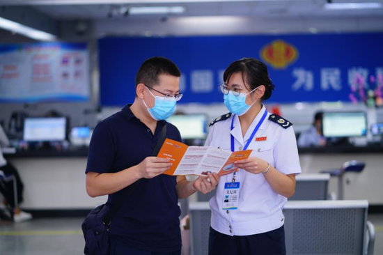 图片说明:办税服务厅税务干部向纳税人宣传税收优惠政策.摄影:傅启旭