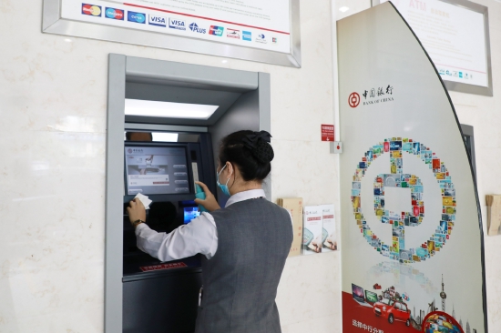 图为海南中行员工对atm取款机进行消毒防疫工作