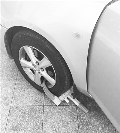 海口一市民没把车停在车位上遭保安锁车轮警告