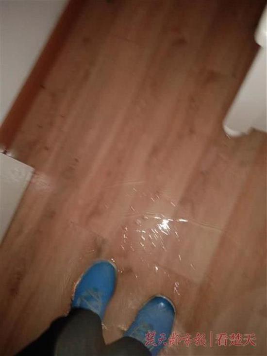 图为张先生新房地板被水浸泡