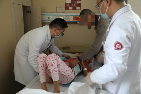 (管床医生王小阵帮助患者佩戴腰部支具)