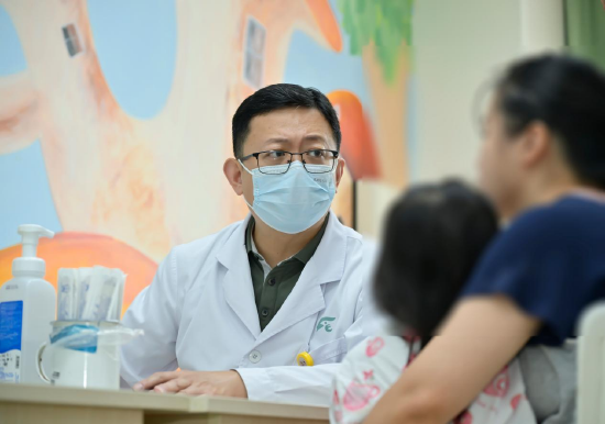 图为在儿童移植术后随访门诊上，熊昊主任医师为患儿提供规范化的全病程管理。