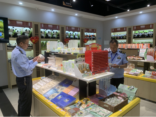 执法人员在景区商户检查商品标签标识,右为周立志