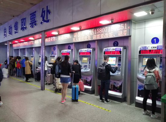 图为4月30日旅客在武昌站自助售取票机取票(陈俊 摄)