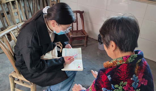 图为甘莹莹（左）向“留守老人”普及药品常识