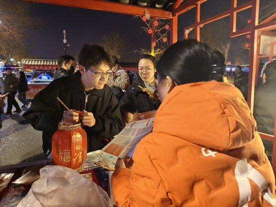 （图片说明：平安志愿者向过往游客科普金融知识）