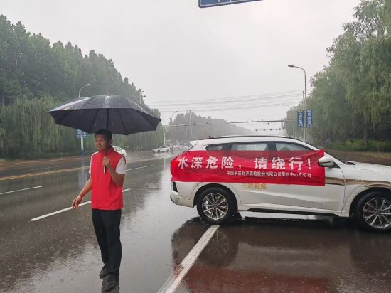 图片：党员志愿者引导车主绕行积水路段