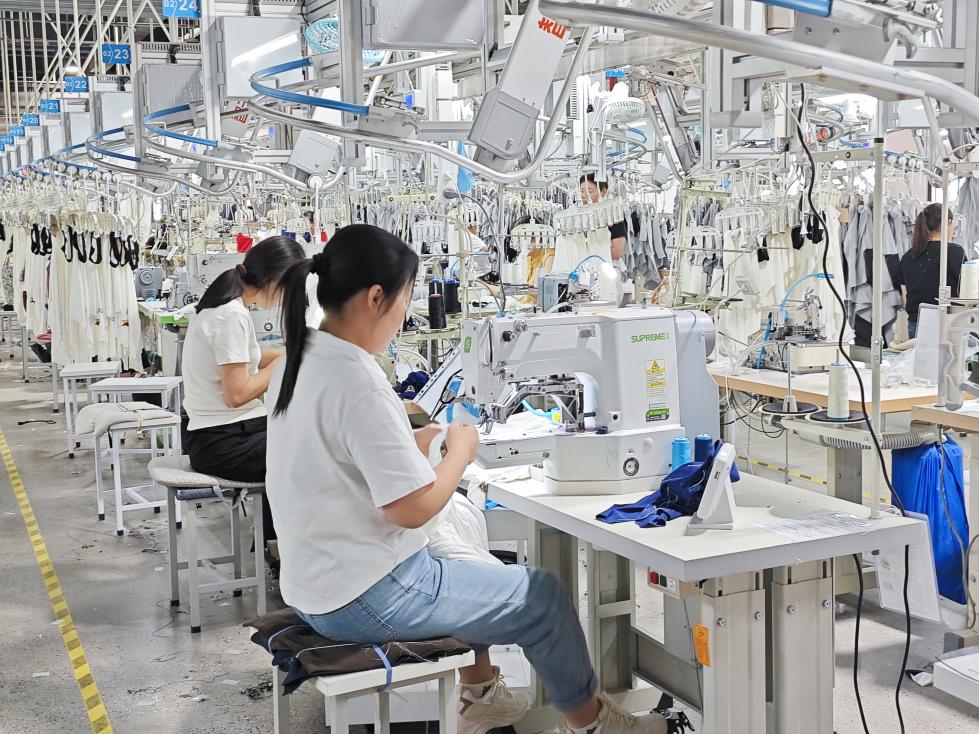 图为智能吊挂流水线上工人赶制服装。