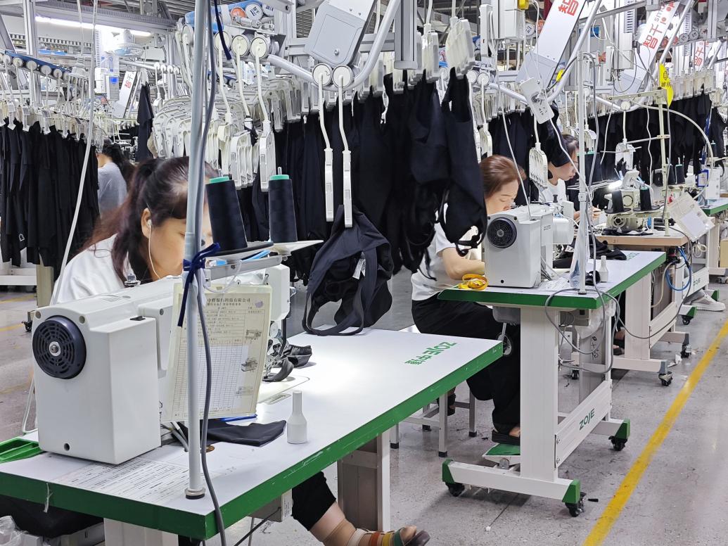 图为智能吊挂流水线上工人赶制服装。