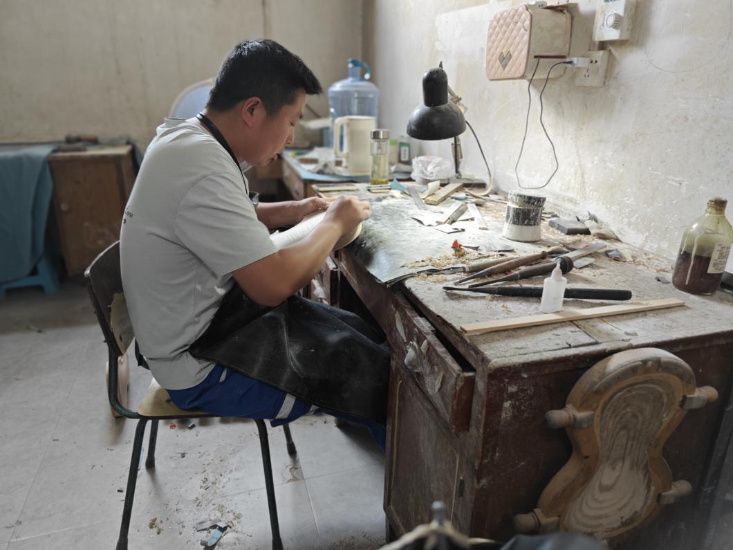 图为手工制琴师宋永稳正在打磨琴身。