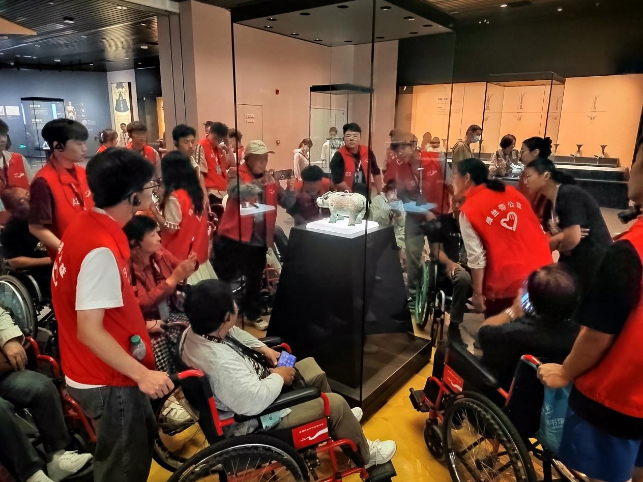 残疾人代表在志愿者的帮助下正在欣赏殷墟博物馆文物