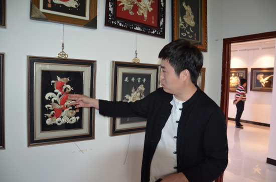 图为赫哲文化传承人解永亮先生正在向队员介绍鱼皮画.