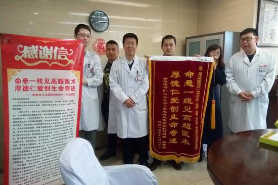 图为患者家属将锦旗和感谢信送到高宏伟主任(中间穿白服者)的手中