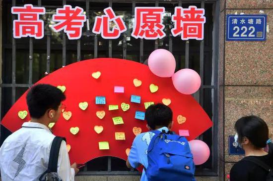 (6月7日,长沙市第一中学考点外,考生在高考心愿墙上写下祝福和心愿.