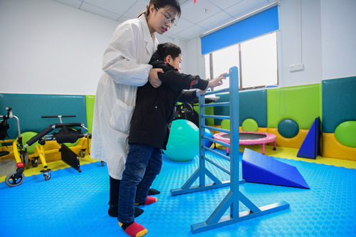 康复治疗师曾祥英(左)在引导7岁脑瘫患儿昊昊(化名)进行行走康复训练