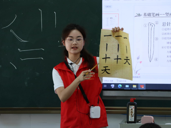 志愿者向学生们示范笔锋的书写