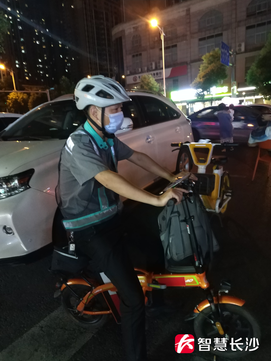 图为守候在木莲路旁某小区夜宵街入口处的滴滴代驾黄师傅(剑裘 摄)