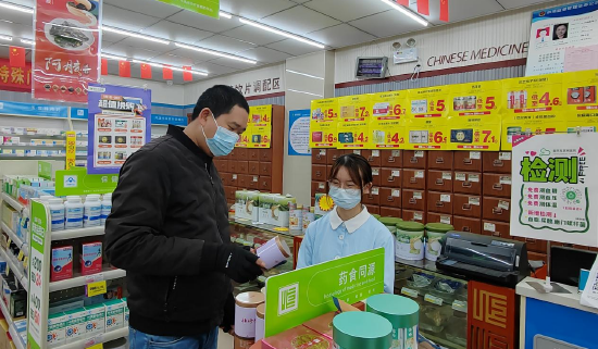 (益丰大药房店员向顾客介绍中药养生产品)
