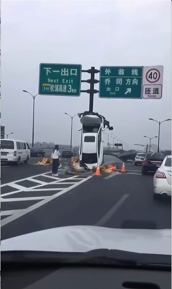 一轿车竖直靠在路上指示牌栏杆。图片来源网络