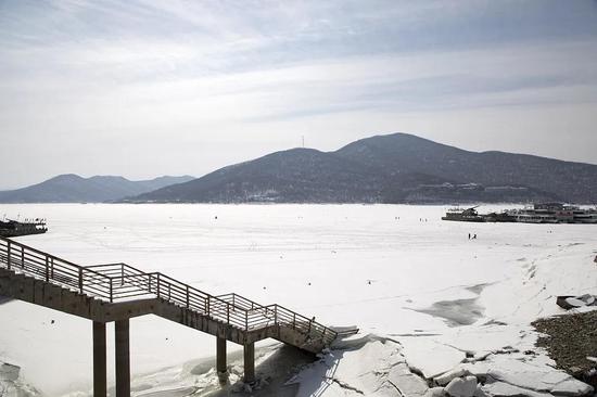 初春时节的松花湖静静地"坐"在山坳之间,白雪皑皑,平平坦坦,静谧无限