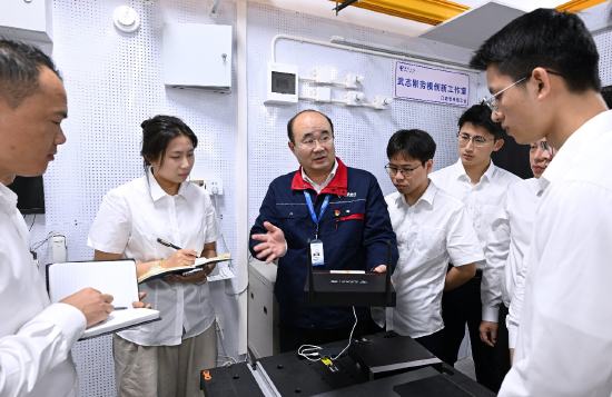 图为武志刚同志（左三）正在向青年员工传授通信技术知识