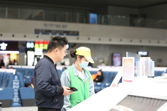 图为志愿者在使用自助设备帮助旅客查询购票信息。张倩 摄