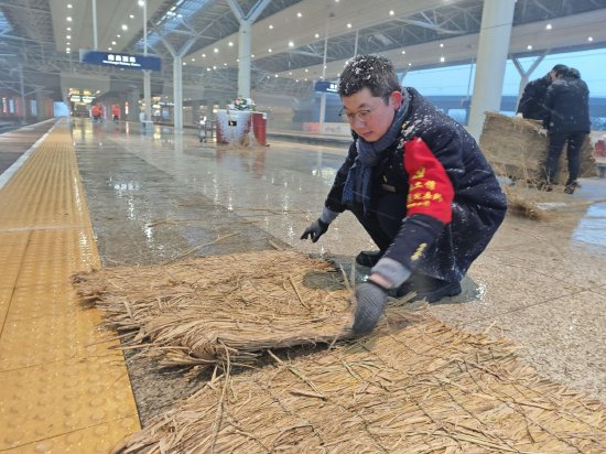 南昌西站工作人员在站台铺设草垫,保障旅客安全出行。 贺婷婷/摄