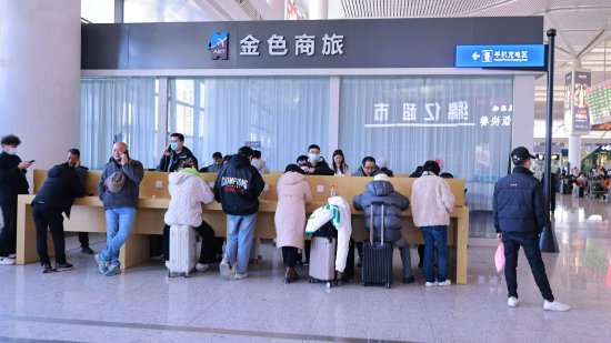 南昌西站旅客正在手机充电区给手机充电。(张杰 摄)