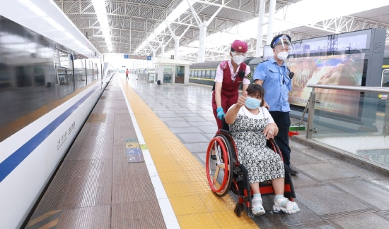南昌客运段列车长正在帮助重点旅客乘车。(吴云峰 摄)
