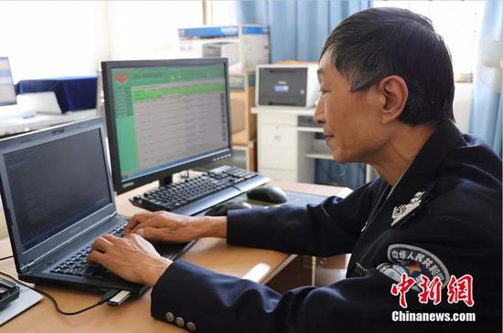 图为头发鬓角已白的陈昆平在编辑程序代码，左侧电脑屏幕上有他研发的“戒毒康复人员信息管理系统”。陶家淇 摄