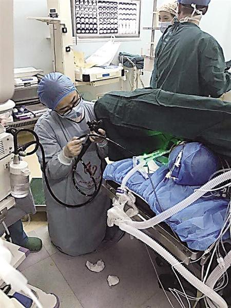 手术中孙文静医生跪地为患者插管进行营养支持 医院供图