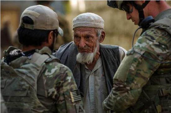 资料图：2012年10月25日，阿富汗巴格拉姆机场外，口译员（左）和美国空军相关人士（右）与村民交谈（新华网）