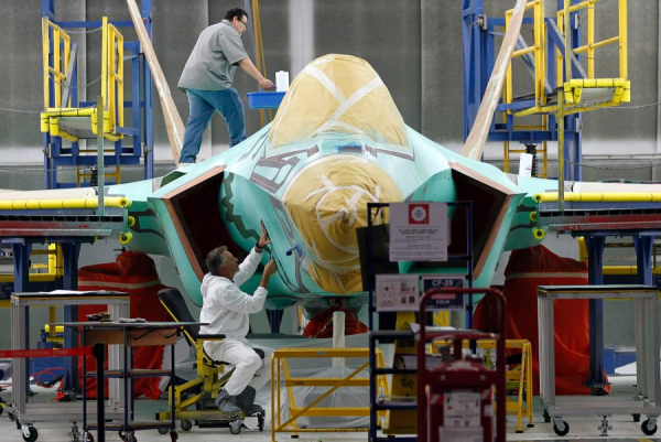 资料图片：工厂技工为F-35战机机身刷保护漆。（图片来源于网络）
