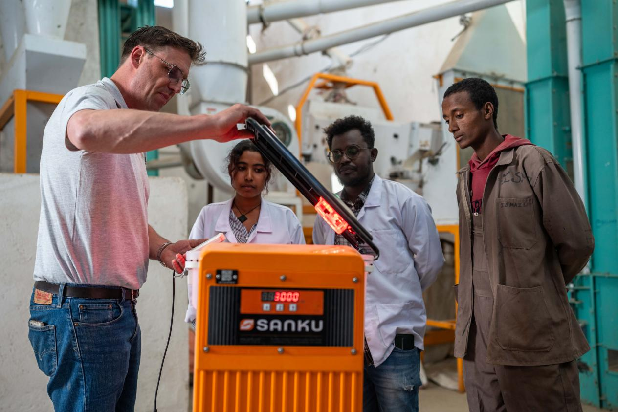 Sanku的聯合創始人費力克斯・布魯克斯-丘奇正在向麵粉廠經理Yeabsra Demle Yimer、工廠及生產主管Biruk Teshome，以及設備操作員Ismael Kassaye（從左到右）講解營養增量機的工作原理。©Rolex/Aurélie Marrier D‘Unienville