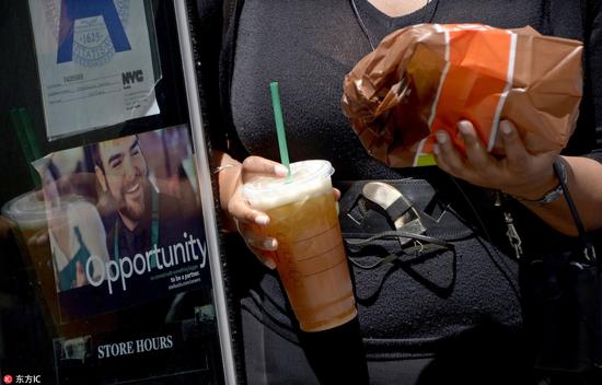 （美国纽约，一名妇女用塑料吸管喝饮料，图片来源：东方IC。）