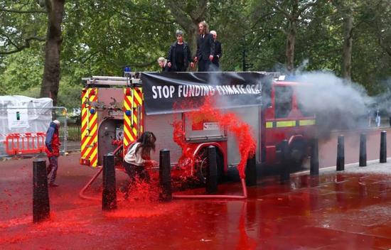  ▲示威者在伦敦的路面大倒“假血”（图via Reuters）