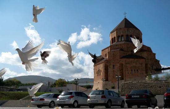 ▲资料图片：10月9日，鸽子在纳卡地区首府斯捷潘纳克特的一所教堂前飞翔。（新华社/美联）