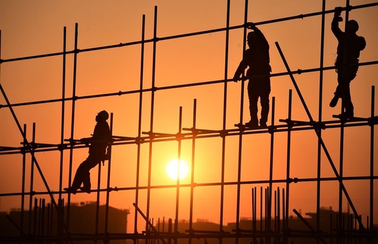 2022年1月1日，在河北雄安新区容西安置房项目D标段施工现场，工人在新年第一缕阳光的照耀下工作。