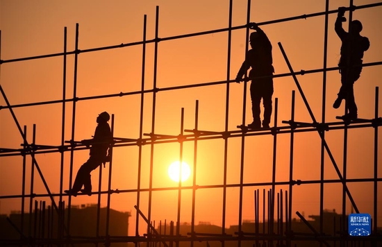 2022年1月1日，在河北雄安新区容西安置房项目D标段施工现场，中铁上海工程局工人在新年第一缕阳光的照耀下工作。新华社发（傅新春 摄）