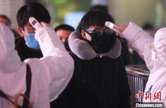 资料图:防疫人员正在给旅客检测体温。泱波 摄